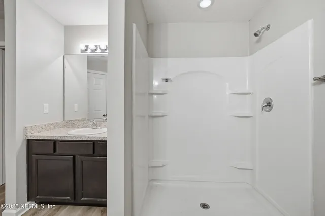 a bathroom with a granite countertop sink a mirror and shower