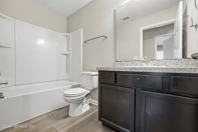a bathroom with a granite countertop toilet sink and mirror