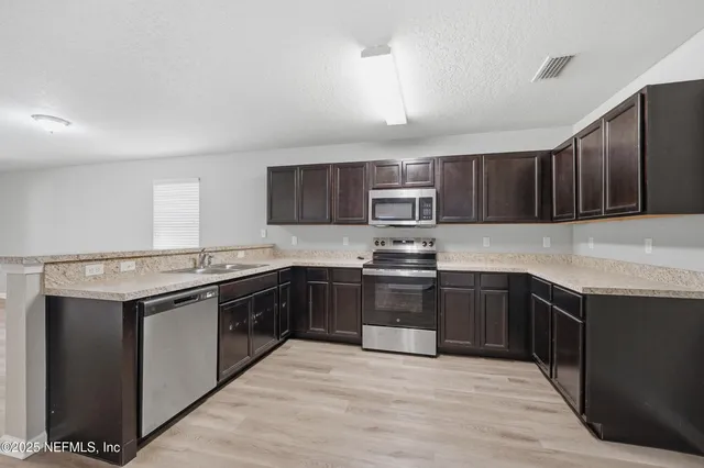 a kitchen with stainless steel appliances granite countertop a stove top oven a sink dishwasher and a microwave oven with cabinets