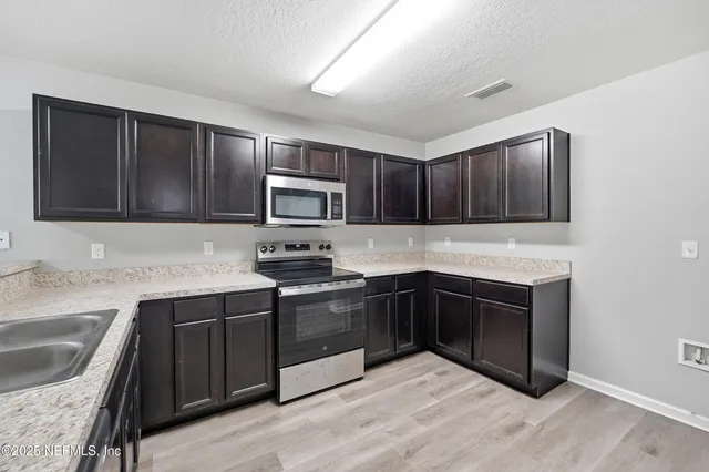 a kitchen with granite countertop a sink cabinets and stainless steel appliances