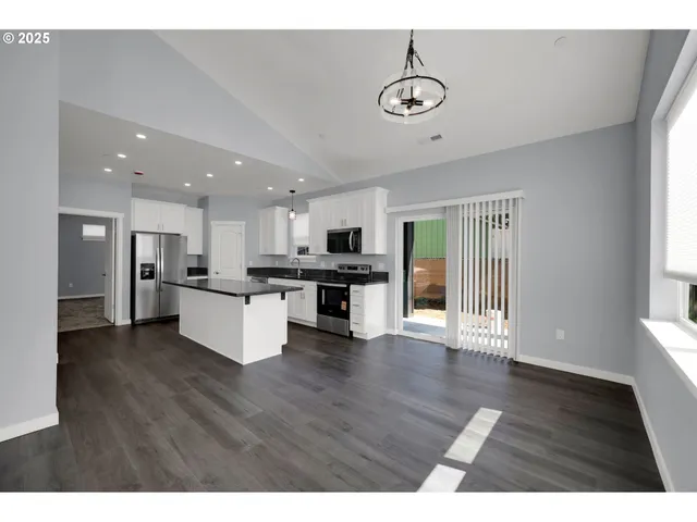 a view of kitchen with refrigerator stove and wooden floor