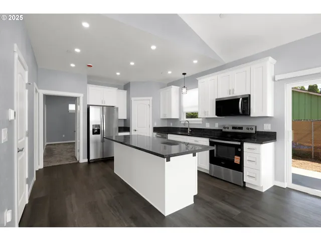 a kitchen with stainless steel appliances kitchen island granite countertop a stove top oven a sink a refrigerator and a granite counter tops