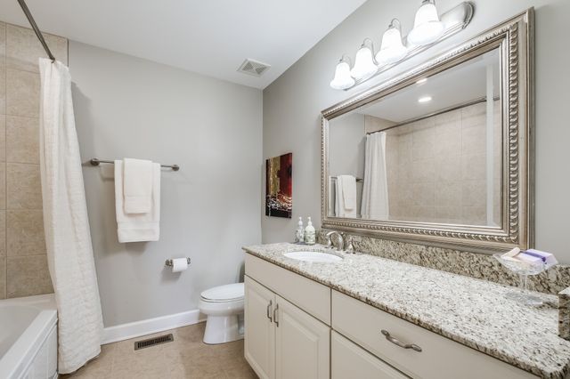 a bathroom with a granite countertop sink a toilet and mirror