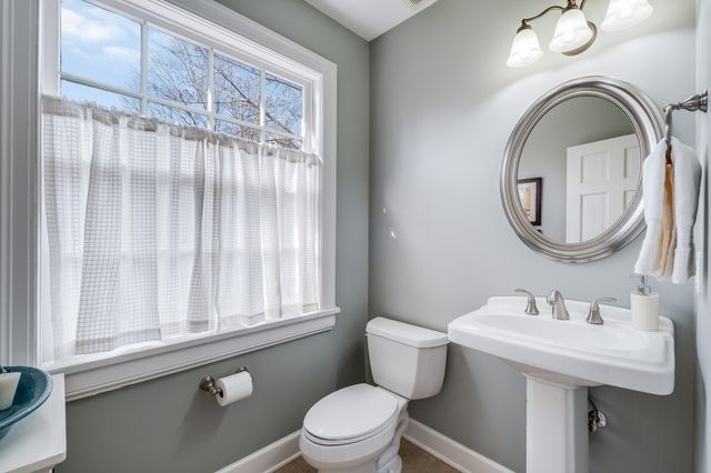 a bathroom with a sink a mirror a toilet and a window