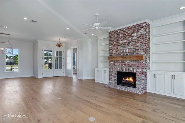 a view of an empty room with wooden floor fireplace and a window