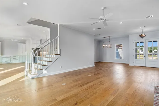 an empty room with wooden floor fan and windows