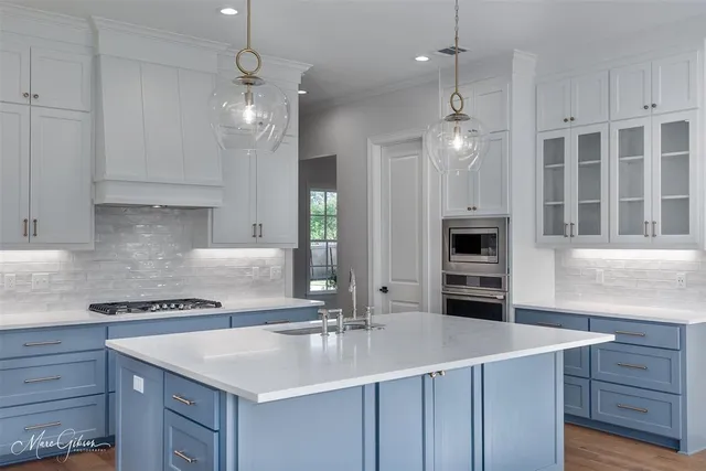 a kitchen with kitchen island granite countertop a sink cabinets and stainless steel appliances