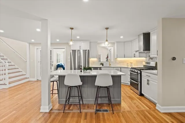 a living room with stainless steel appliances furniture refrigerator and a kitchen view