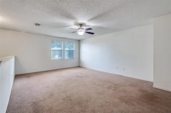 an empty room with windows and ceiling fan