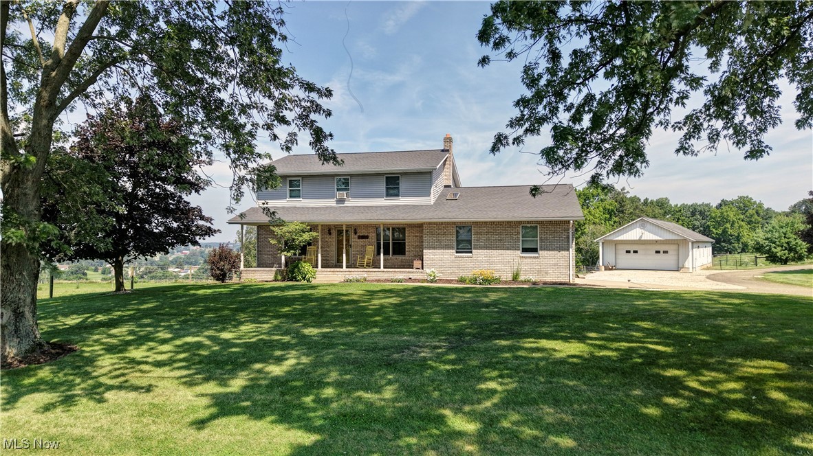 17198 Harrison Road Navarre, OH 44662 - Photo 1 of 45 View of front facade featuring an outbuilding, a detached garage, brick siding, a front lawn, and covered porch