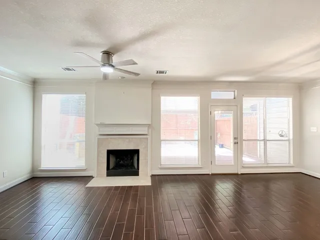 an empty room with wooden floor fireplace and windows