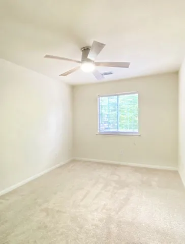 an empty room with a ceiling fan and a window