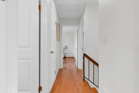 a view of a hallway with wooden floor and staircase
