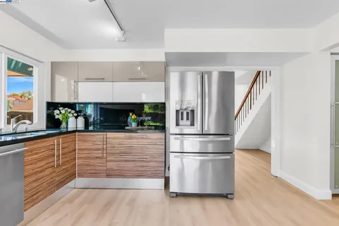 a kitchen with granite countertop a refrigerator and a wooden floor