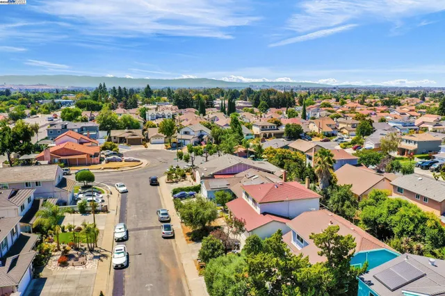 an aerial view of a city with lots of residential buildings ocean and mountain view in back
