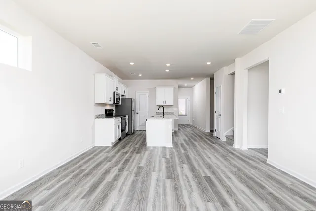 a view of large kitchen with wooden floor and stainless steel appliances