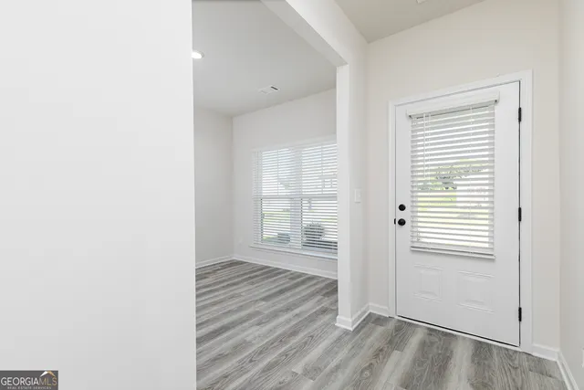 an empty room with wooden floor and windows