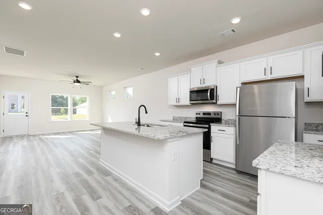 a kitchen with stainless steel appliances granite countertop a refrigerator stove a sink and a refrigerator