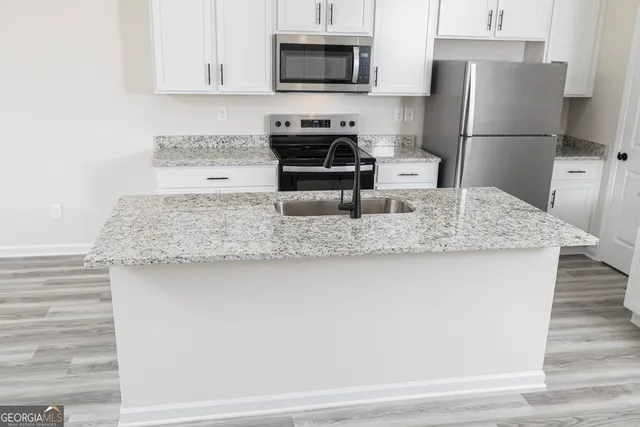 a kitchen with kitchen island granite countertop a stove a sink and a microwave