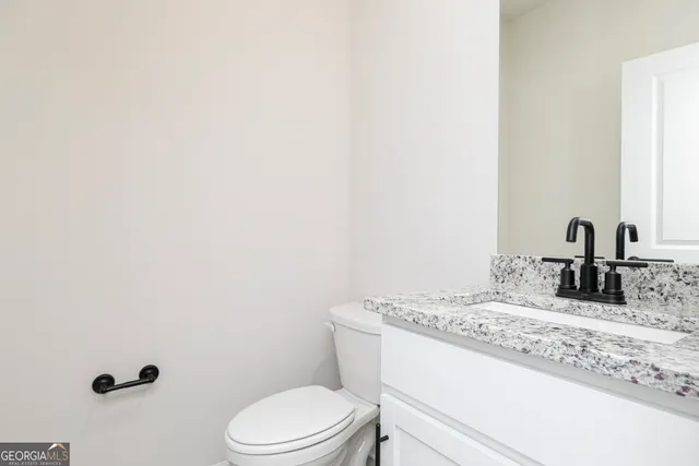 a bathroom with a granite countertop sink toilet and mirror