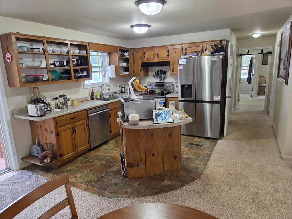 208 Ledford Chapel Road Hayesville, NC 28904 - Photo 9 of 35 a kitchen with stainless steel appliances granite countertop a refrigerator a stove a sink a dining table and chairs with wooden floor