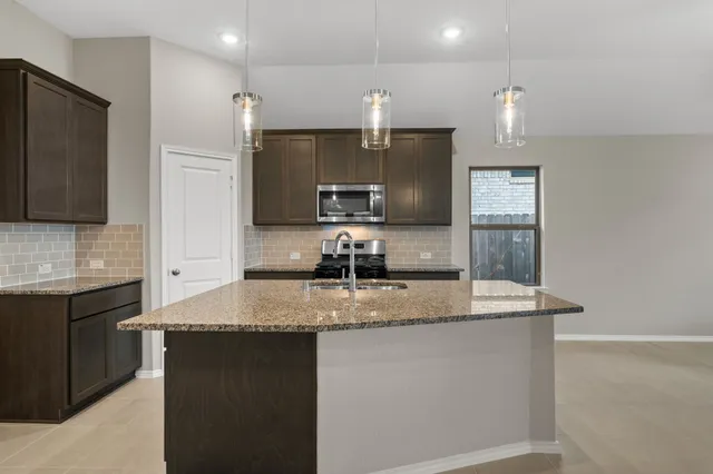 a kitchen with kitchen island granite countertop a sink a counter top space stainless steel appliances and cabinets
