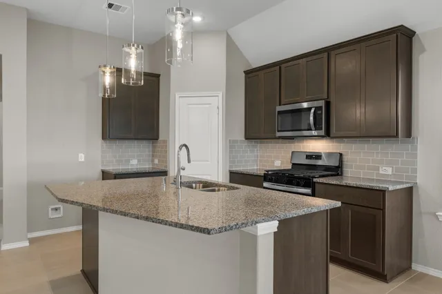 a kitchen with granite countertop a sink a counter top space appliances and cabinets