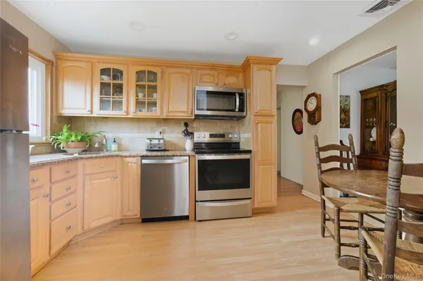 a kitchen with stainless steel appliances granite countertop a stove top oven a sink a dining table and chairs with wooden floor