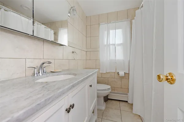 a bathroom with a granite countertop sink a toilet and bathtub