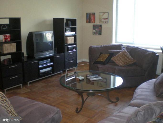 4100 W Street Northwest, Unit 510 Washington, DC 20007 - Photo 2 of 12 a living room with furniture a flat screen tv and kitchen view