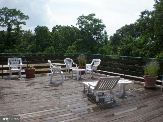 4100 W Street Northwest, Unit 510 Washington, DC 20007 - Photo 12 of 12 a view of a roof deck with table and chairs with wooden floor and fence