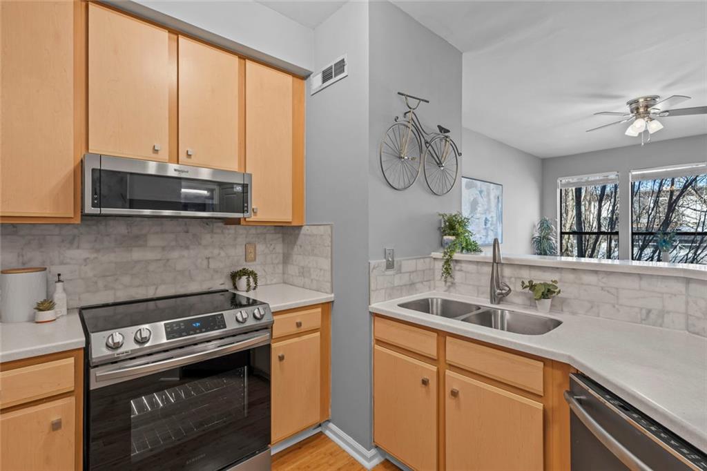 821 Ralph McGill Boulevard Northeast, Unit 3301 Atlanta, GA 30306 - Photo 11 of 31 a kitchen with stainless steel appliances a white sink a stove and a window
