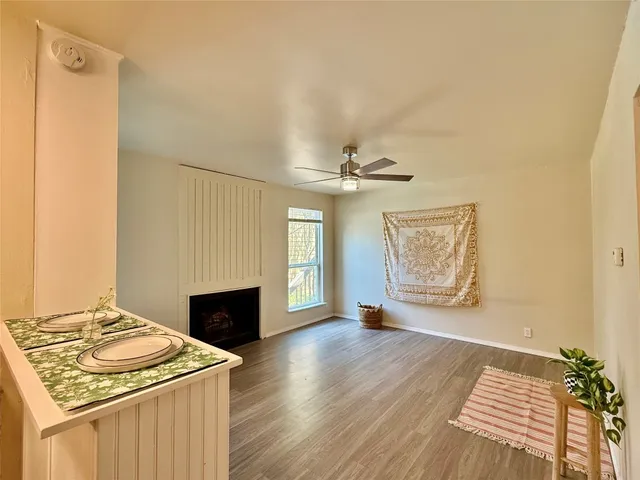 a view of an empty room with wooden floor and a fireplace