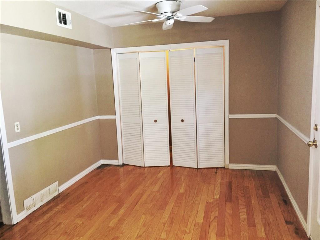 216 Elm Street Hurst, TX 76053 - Photo 8 of 17 Hardwood flooring throughout, featuring a ceiling fan with integrated lighting, bi-fold louvered closet doors, and two-tone wall treatment with a white chair rail