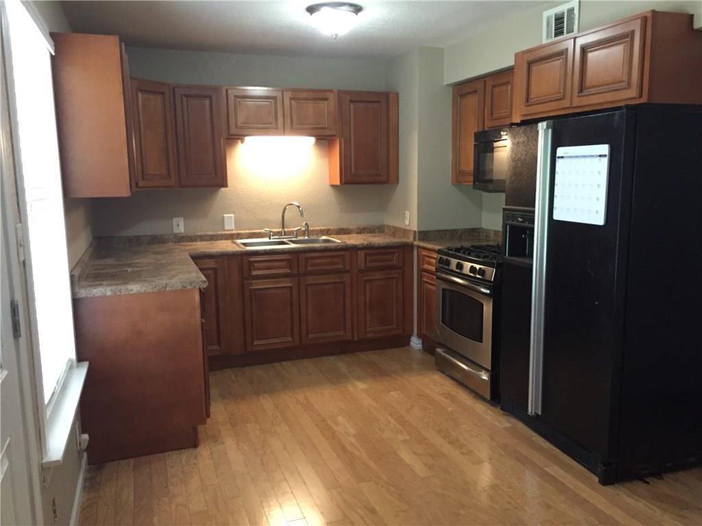 216 Elm Street Hurst, TX 76053 - Photo 9 of 17 Kitchen featuring wood-finish flooring, dark wood cabinetry, laminate countertops, and stainless steel appliances including a range and microwave