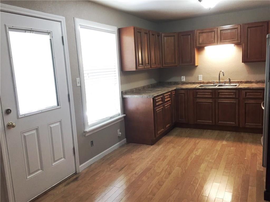 216 Elm Street Hurst, TX 76053 - Photo 10 of 17 Kitchen featuring wood-finish flooring, dark wood cabinetry, a double basin stainless steel sink, and a counter-depth refrigerator