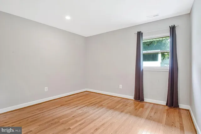 a view of an empty room with wooden floor and window