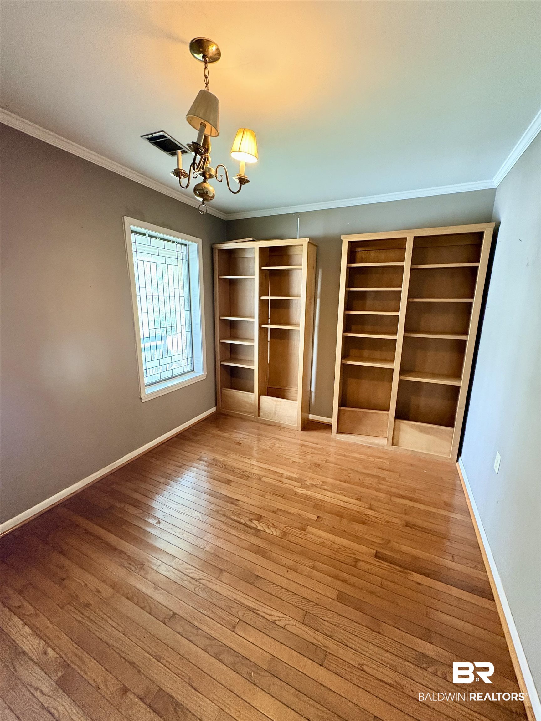 1018 Bates Road Evergreen, AL 36401 - Photo 10 of 21 Unfurnished bedroom featuring ornamental molding, light wood-style flooring, suspended lighting, and multiple closets