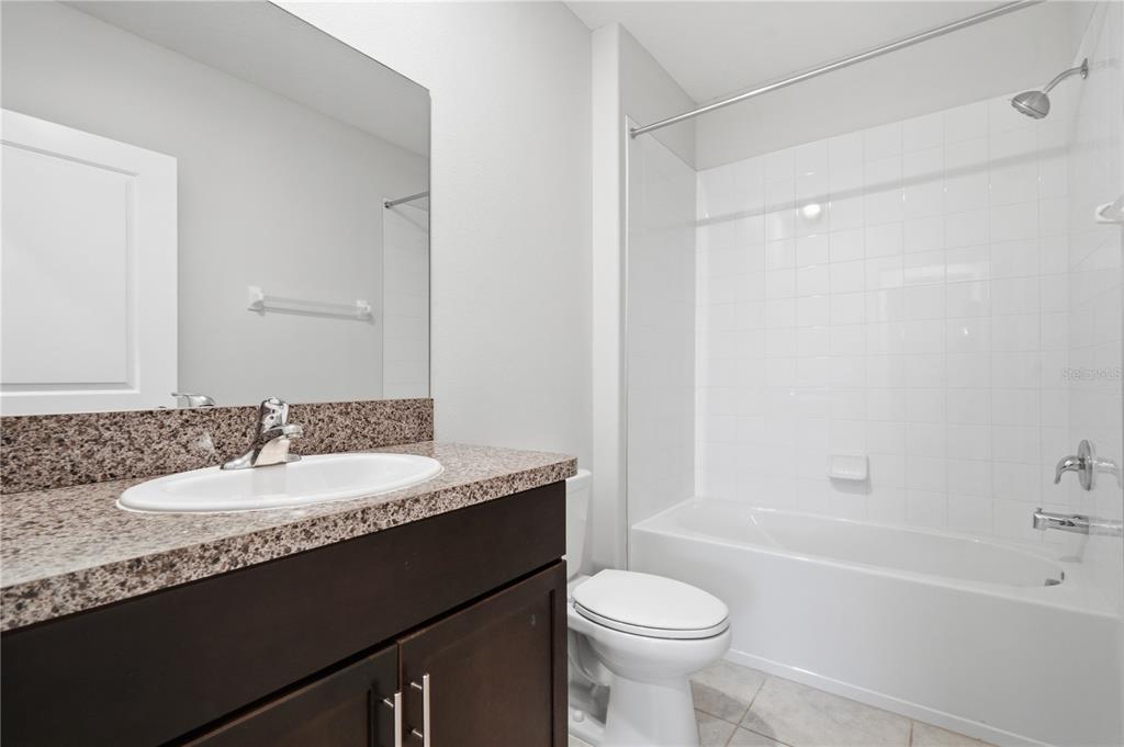 5223 Dandelion Street Apollo Beach, FL 33572 - Photo 15 of 19 a bathroom with a granite countertop sink a toilet a mirror and shower