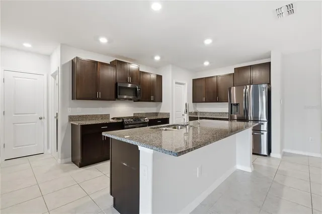 a kitchen with stainless steel appliances granite countertop a sink and a refrigerator