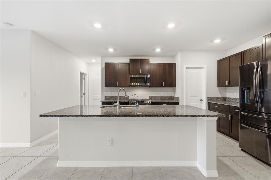 5223 Dandelion Street Apollo Beach, FL 33572 - Photo 6 of 19 a large kitchen with granite countertop a sink and stainless steel appliances