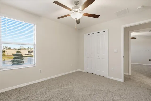 an empty room with a window and a ceiling fan