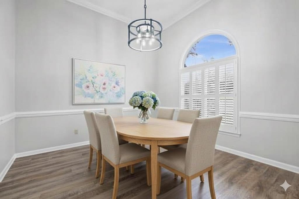 Dining room with dark wood-type flooring, ornamental molding, and a chandelier