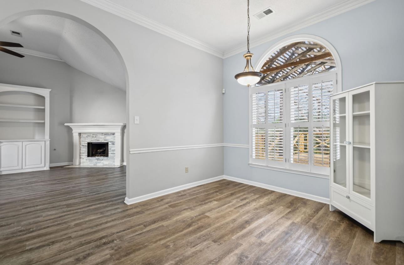 230 West Powell Road Collierville, TN 38017 - Photo 8 of 14 Unfurnished dining area featuring crown molding, a stone fireplace, dark wood-type flooring, built in features, and ceiling fan