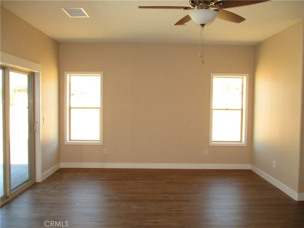 24236 Cahuilla Road Apple Valley, CA 92307 - Photo 31 of 48 an empty room with wooden floor fan and windows