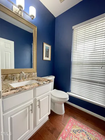 a bathroom with a granite countertop toilet a sink and a mirror