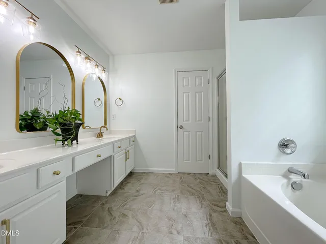a spacious bathroom with a tub sink and mirror