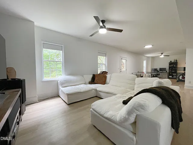 a living room with couches and kitchen view with wooden floor