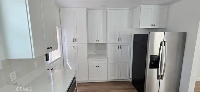a view of kitchen with refrigerator stove and white cabinets