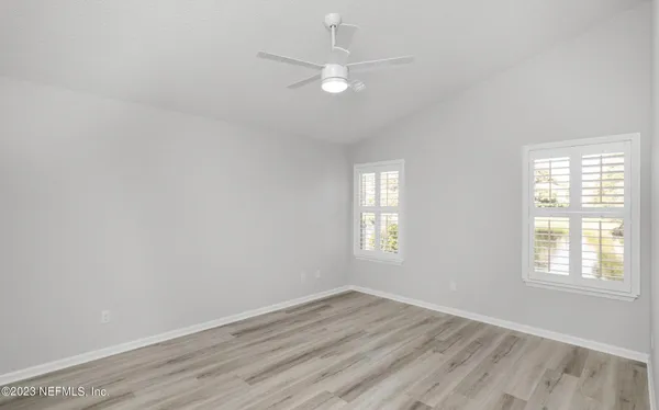 an empty room with wooden floor and fan